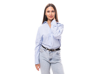 young stylish caucasian model woman with makeup and with dark straight hair dressed in a blue blouse on a white background with copy space