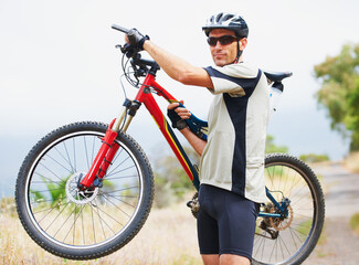 Portrait, bicycle and fitness with a man in the mountains for cardio training, recreation or summer hobby. Sports, cycling and freedom with a confident young athlete outdoor for eco friendly exercise
