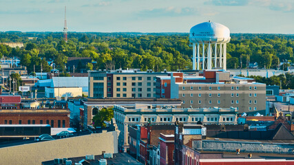 Downtown Muncie, IN aerial of city buildings leading to American Water tower and green trees
