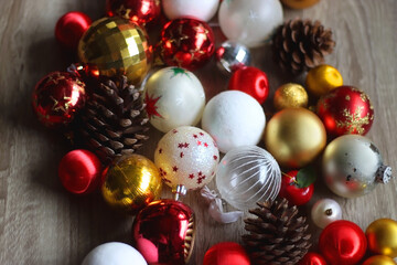 Pine cones and red, golden and white Christmas ornaments on wooden background. Selective focus.