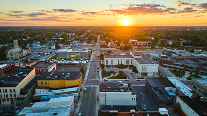 Downtown aerial of Muncie, IN city with golden sun setting on horizon