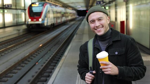 Ethnic man waiting for a train with hot coffee cup  