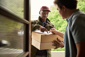 Man signing for a courier delivery at his front door