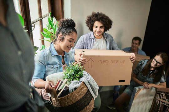 Diverse group of young people moving in their new shared apartment and carrying boxes