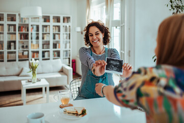 Excited Woman Showing Ultrasound to Friend Over Lunch