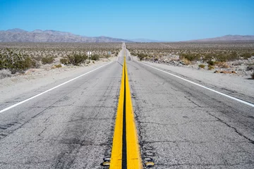 Gartenposter Empty highway along Mojave desert with cracks on the asphalt, California © Bisual Photo