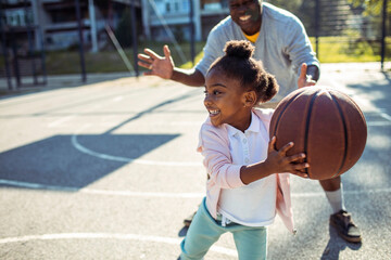 Grandfather Coaching Granddaughter in Basketball Outdoors