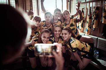 Female football players posing for group photo in locker room