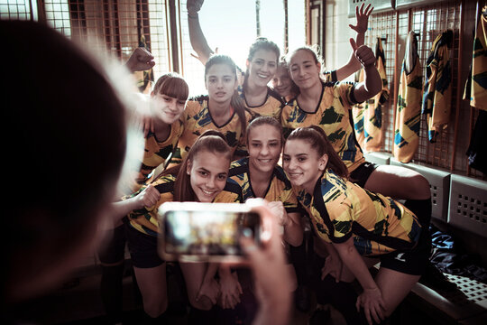 Female football players posing for group photo in locker room