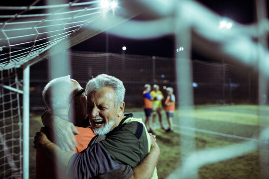 Senior Soccer Players Celebrating a Goal at Night