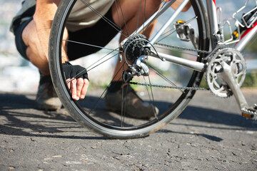 Check, wheel and hand on bicycle with road, street and outdoor exercise with flat tire. Cycling,...