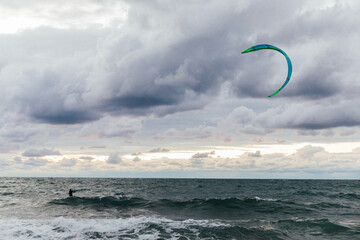 Kitesurfing athlete riding waves in a storm - obrazy, fototapety, plakaty