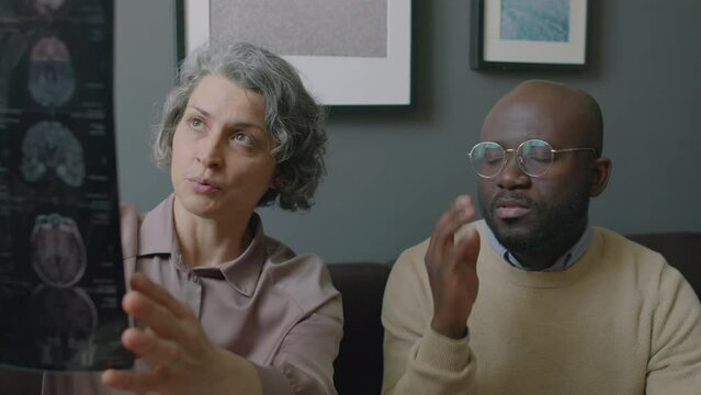 Experienced sleep doctor explaining results of MRI brain exam to African American patient during medical consultation in somnology clinic