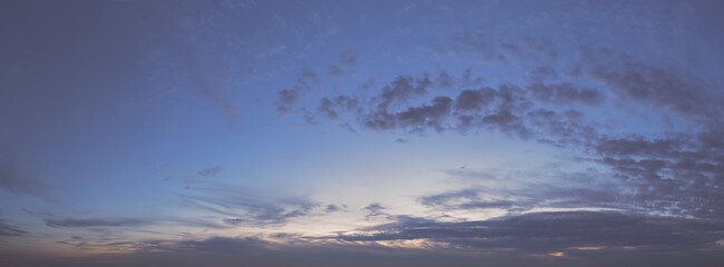 Panorama of a moody and wild cloudscape during blue hour after sunset. Flat gradation - ready to be edited.
