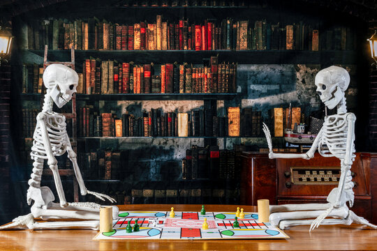 skeletons on oak table with antique radio and old library background playing parcheesi