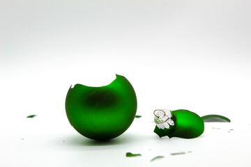 A broken green Christmas ornament on a white background.