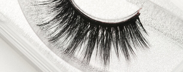 Obraz premium Black long false eyelashes close-up on white background. Self-adhesive eyelashes, eyelash extensions, mascara effect.