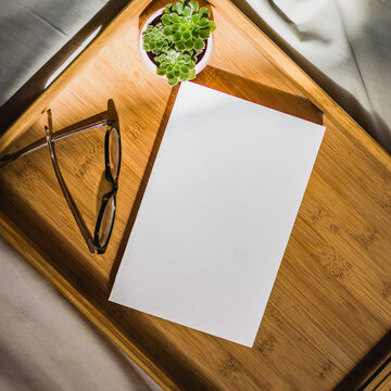 Blank book and reading glasses on wooden tray 