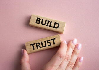 Build trust symbol. Wooden blocks with words Build trust. Beautiful pink background. Businessman hand. Business and Build trust concept. Copy space.