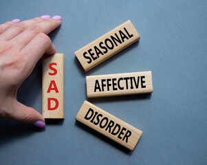 Sad - Seasonal Affective Disorder symbol. Wooden blocks with words Sad. Businessman hand. Beautiful grey background. Business and Sad concept. Copy space.