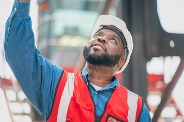 Portrait of African Engineer or foreman wears PPE checking container storage with cargo container background at sunset. Logistics global import or export shipping industrial concept. - obrazy, fototapety, plakaty