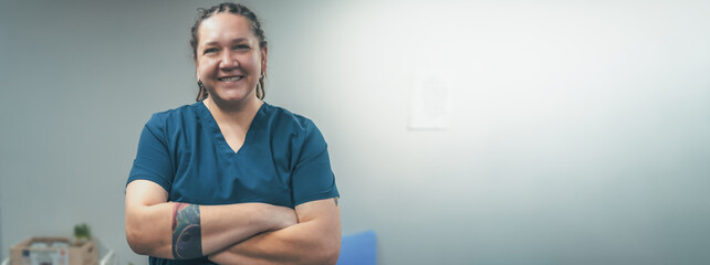 Portrait of smiling female doctor or veterinarian in uniform in clinic. Friendly woman medic looks at camera and smile, horizontal banner image with copy space for text. - obrazy, fototapety, plakaty