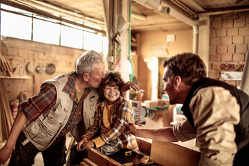 Young Boy Learns Woodworking Skills from His Elderly Grandfather and Father in a Workshop