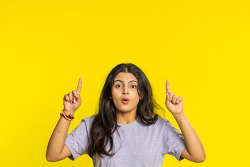 Indian woman showing thumbs up pointing overhead, above head empty place, advertising area for commercial text copy space for goods promotion advertisement. Arabian girl isolated on yellow background - obrazy, fototapety, plakaty