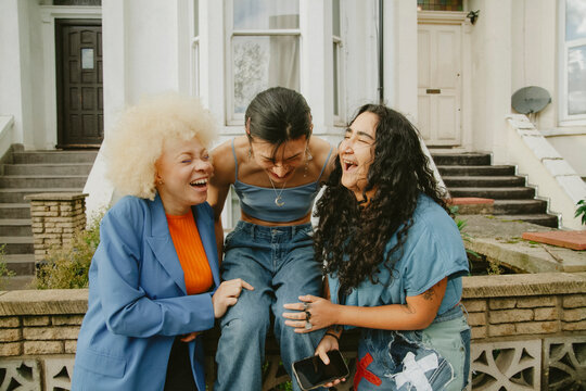 Three multiracial friends in trendy outfits having fun in urban area