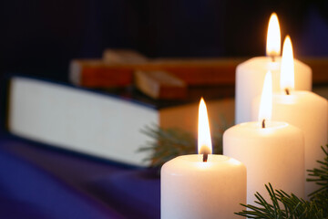 Four burning Advent candles with Bible and cross in background, religious symbol concept 