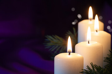 Four burning Advent candles with spruce twigs on purple background, religious symbol, copy space