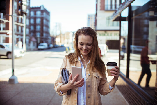 Young Woman Enjoying Coffee and Smartphone on City Street