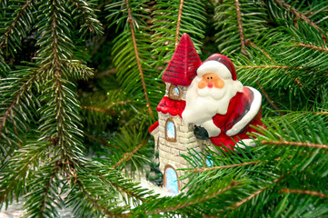 Obraz premium Santa Claus on a house near the branches of a Christmas tree. Background for New Year and Christmas.