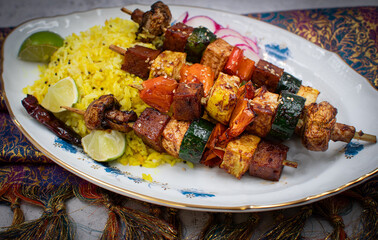 Yellow rice and vegan skewers consisting of seitan, mushrooms, zucchini, pepper. Oval stylish porcelain plate.