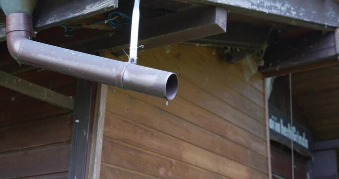 Old house gutter pipe dripping rain water. Real time, close up, no people