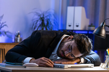 Bored sleepy Indian businessman worker working on laptop computer leaning on hand falling asleep at office table desk. Exhausted tired freelancer workaholic young man. Employment, occupation, workless - obrazy, fototapety, plakaty