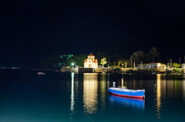 Night view of Greek church and boat on the sea shore in Gytheio, Peloponnese region, Greece. Long exposure