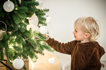 A little girl helps to decorate the Christmas tree in preparation for Christmas