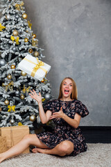 Beautiful woman opening gifts at christmas tree for new year