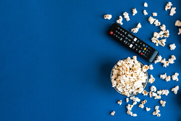 Popcorn and decorative pumpkins with TV remote on a blue background with copy space. Movie night...