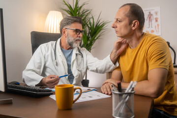 Friendly middle-aged man doctor checking sore throat or thyroid glands