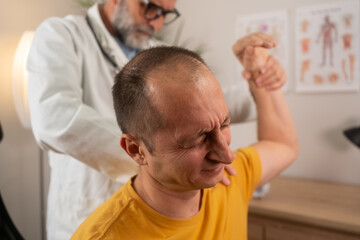 Fototapeta premium A man with shoulder pain goes to the doctor, The doctor diagnoses the patient's arm pain and shoulder pain. Concept of physical therapy and rehabilitation. Physiotherapist doing healing treatment 