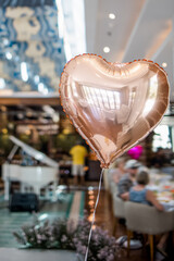 Elegant table set up for Valentine day, anniversary or romantic Dinner, decorated with flowers, candles and tableware with heart shaped pink balloon in foreground