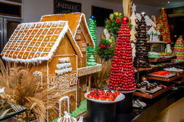 Gingerbread houses with cream frosting and sugar icing displayed for festive catering buffet among other variety of different desserts and sweets.