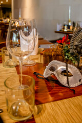 Christmas dinner table set up in restaurant with festive carnival masks, ornaments, decorations and tableware