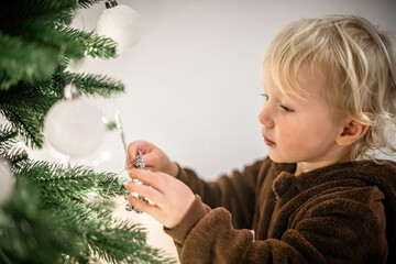 Cute little girl playing with christmas tree at home in the living room