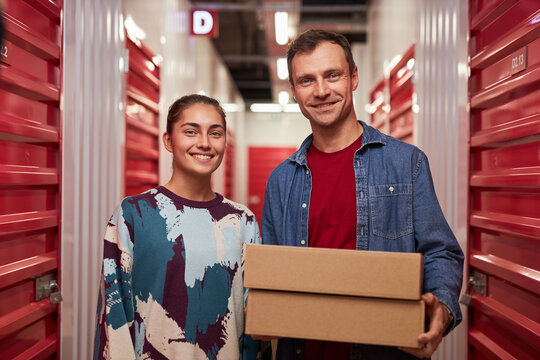 Happy couple standing in corridor of self-storage facility unit