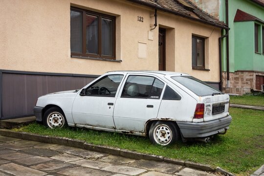 Wreck of white Opel Kadett car parked in front of the house