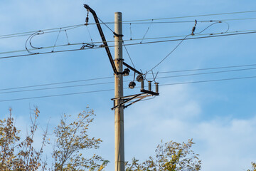 Electrified railway pole on blue sky background. Electric power supply lines on pillars along...