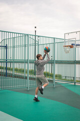Boy teenager playing basketball at city playground. Active life, hobby, sports for children